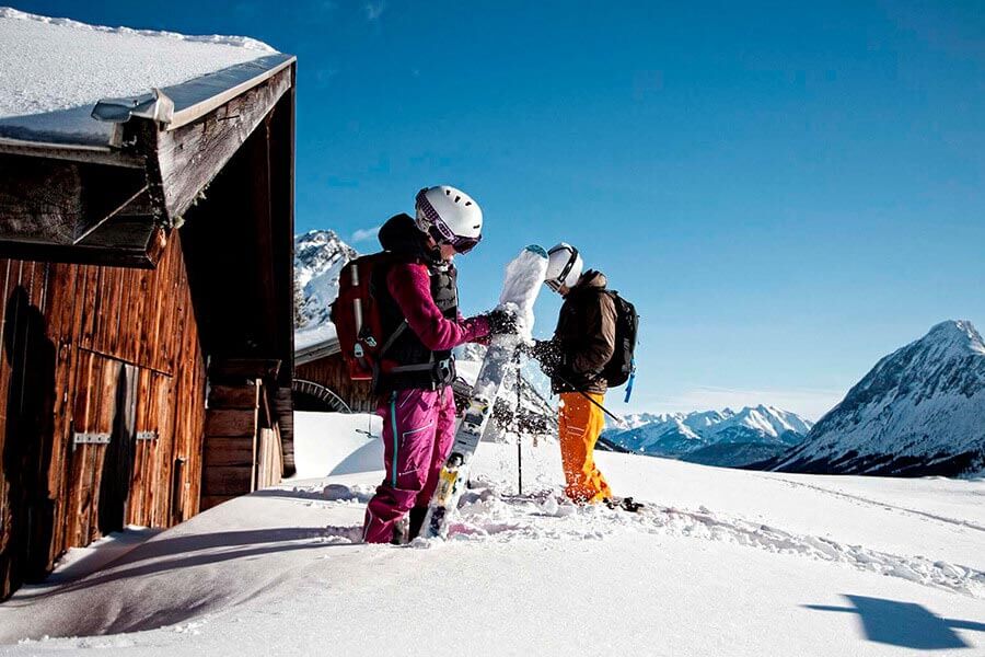 Zwei Skifahrer wischen den Schnee von Ihren benutzten Skies